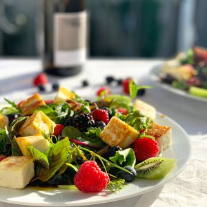 Salatteller mit Beeren und Himbeere im Vordergrund