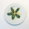 Teller mit Schwarzkohl-Malfatti an Ingwer-Butter-Sauce auf weißem Telller