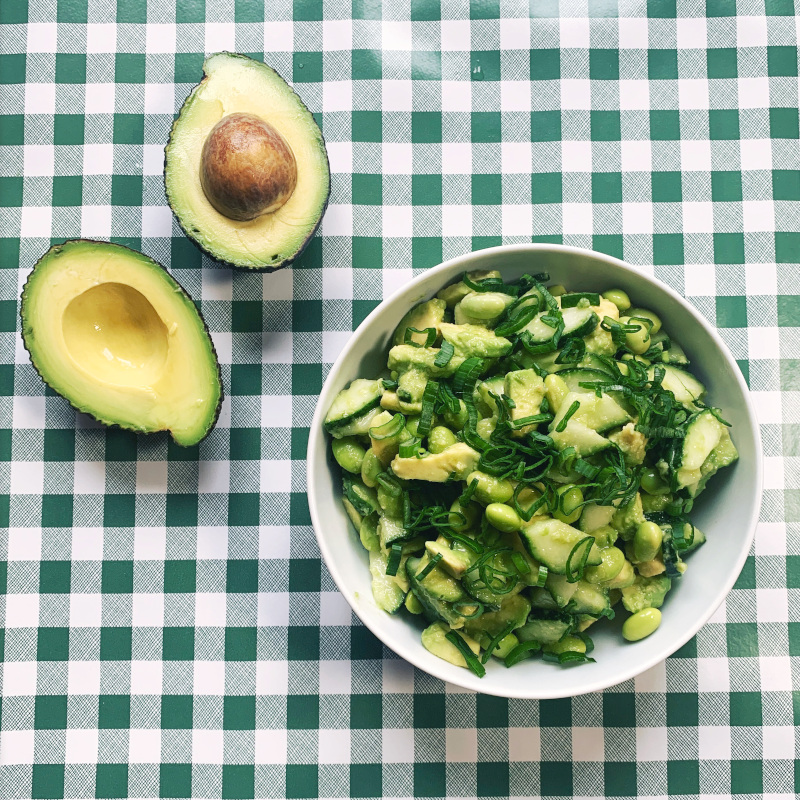Schüssel mit Avocado-Gurken-Salat auf grüner-karierter Tischdecke