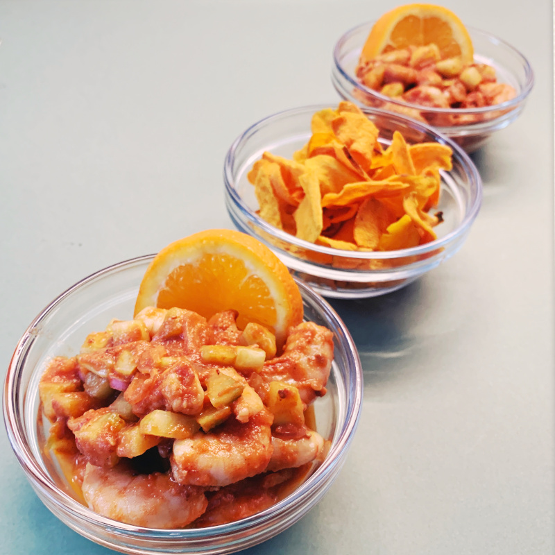 Shrimp-Ceviche in Glasschälchen garniert mit Orangenscheibe und serviert mit Süßkartoffel-Chips
