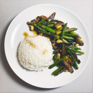 Grüner Spargel mit Shiitake und Reis auf weißem Teller
