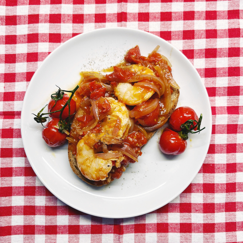 Balsamico-Tomaten mit Scampi auf Bruschetta auf weißen Teller serviert