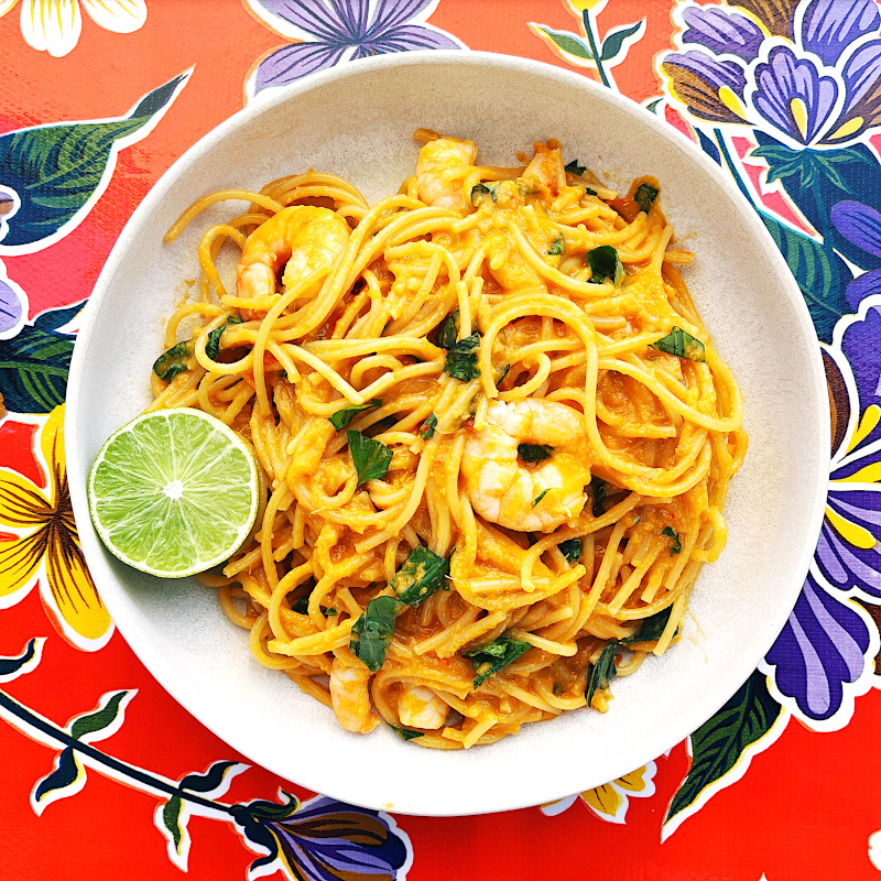 Teller mit cremiger Thai-Spaghetti und Limette auf bunter Tischdecke
