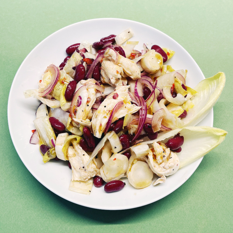 Chicorée-Salat mit roten Bohnen, Mozzarella und Sweet-Chili-Dressig auf weißem Teller
