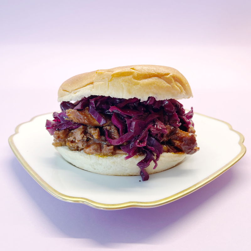 Pulled-Duck-Burger mit Rotkohl auf Teller mit Goldrand