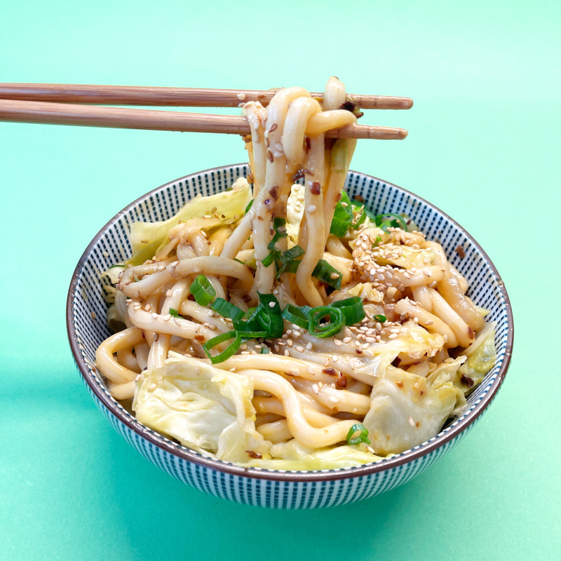 Asia-Nudeln mit Tahini-Chili-Crisp Dip in blau-weißer Nudel-Bowl und Stäbchen