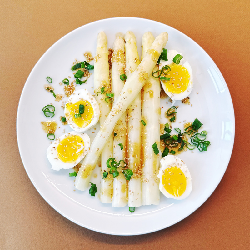 Weißer Teller mit Spargelsalat mit Ei und Miso-Sesam-Dressing