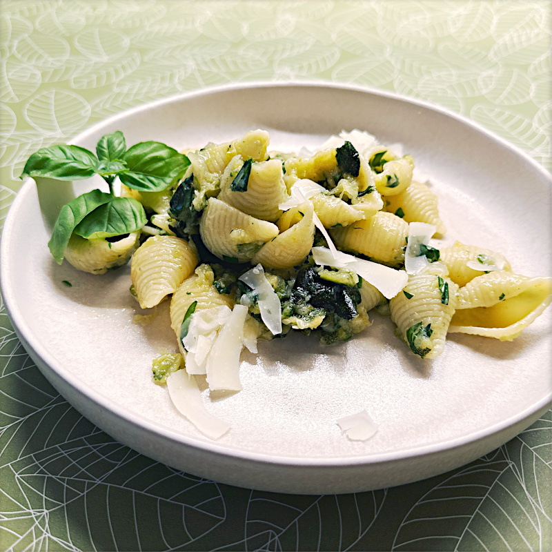 Pasta mit Zucchini-Crème, Zitrone und Basilikum auf weißem Teller