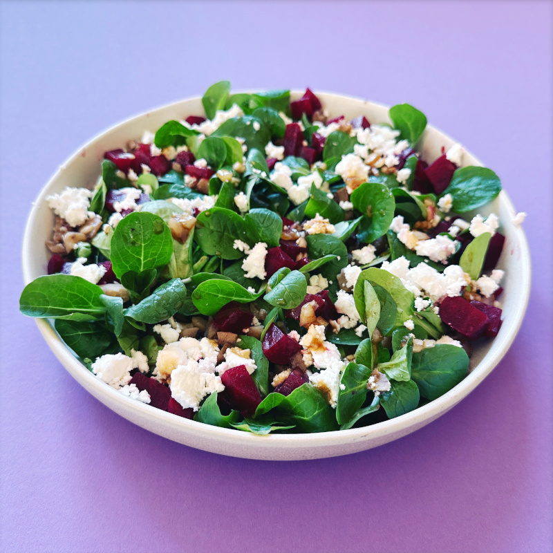 Feldsalat mit Maronen und rote Bete in einem weißen Teller auf einer violetten Tischdecke