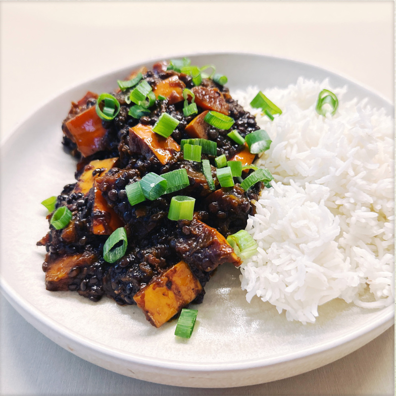 Scharfe Kürbis-Linsen Mayo-Style auf einem weißen Teller mit einer Portion Reis