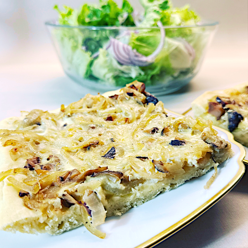 Ein Stück Zwiebelkuchen auf weißem Teller mit Goldrand
