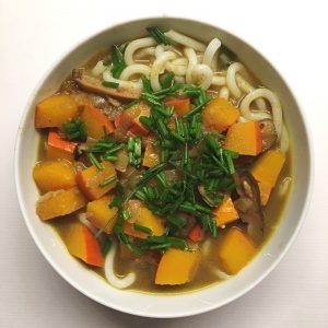 Weiße Schüssel mit Nudeln in Curry-Sauce mit Kürbis (Kare Udon)
