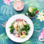 Teller mit Sommerrollen Salat mit Garnelen auf bunter Tischdecke