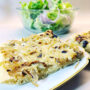 Ein Stück Zwiebelkuchen auf weißem Teller mit Goldrand